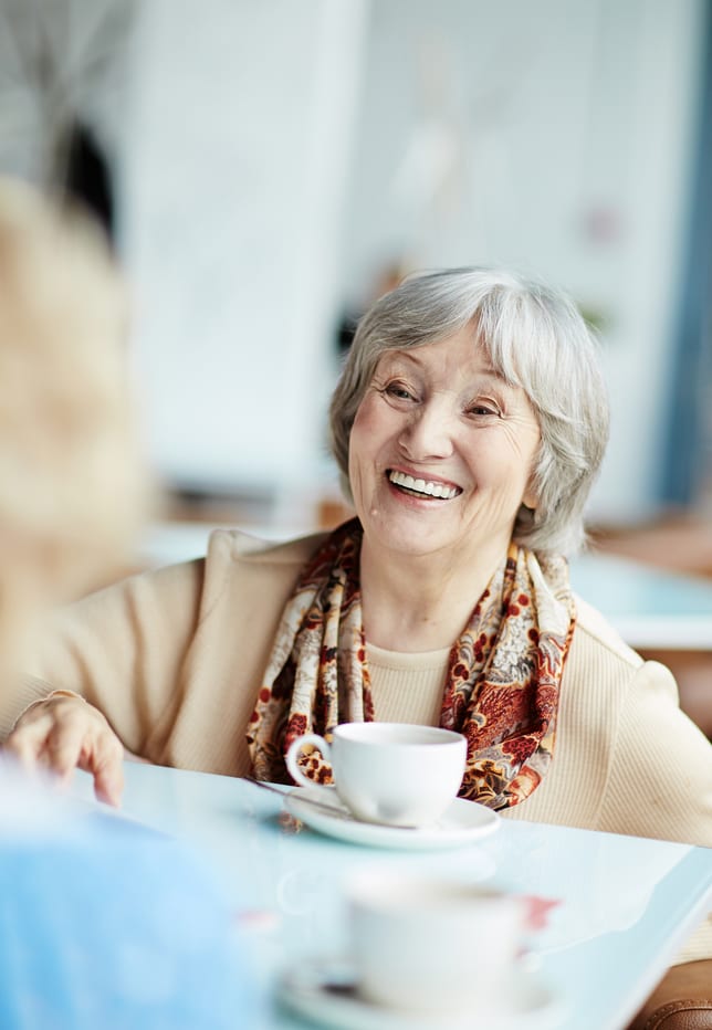 Elderly woman smiling while drinking tea