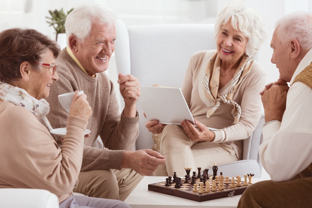 Cheerful seniors talking to each other while playing chess